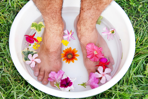 Hairly legs in a basin filled with floating flowers and water
