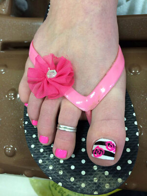 A female foot with pink polish nails and contrasting design on the big toe; designed by Binh's pedi professionals