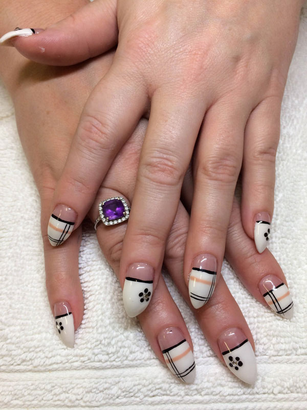 Gel claws in ivory with ebony flourishes and contrasting designs on the ring fingers created by the nail artisans at Binh's on 17th.