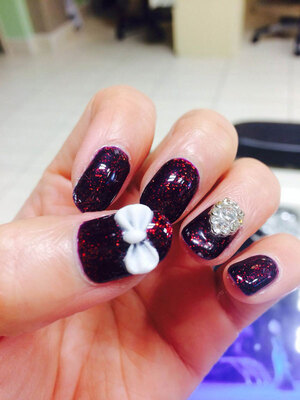 Glitter in the dark purple gel cast along with white accents create 3D magic from Binh's Nails.