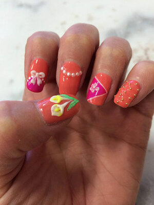 A woman's hand with nails painted in various shades and 3D decorative flourishes; added by Edmonton's Binh's Nails
