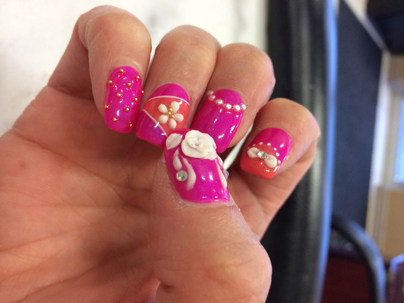 Elements such as flowers and jewels make a dazzling addition to your look Fingernails painted pink with white 3D flowery features are available at Binh's