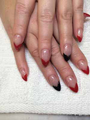 Female fingers with nails sharpened to a point and Vee-shaped polish on the tips in red and black from Binh's manicure specialists