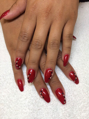 Womanly hands with deep red polish and gem elements produce a lovely look at Binh's Nails in Edmonton East