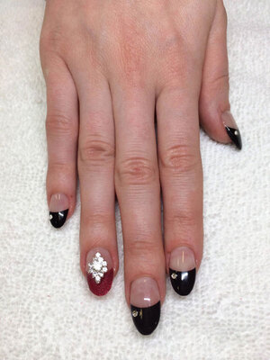 A woman's hand with dark nail tips and jewelled adornments create an alluring look from Binh's Nail Salon