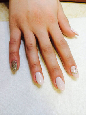 Oval gel nails in gleaming ivory with golden glitter accents present a powerful look from Binh's Nails in East Edmonton..