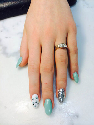 A lady's hand featuring nails in robins egg blue with the ring and index fingers in contrasting styles from Binh's manicures