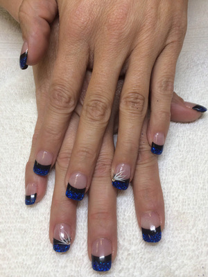 Feminine fingernails with clear polish, blue tips, glitter and white artistic touches on the ring fingers is a beautiful Binh's Nail design.