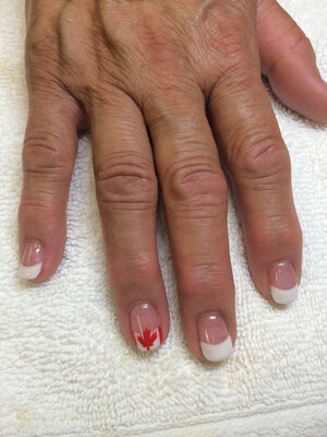 Oval nails with French tips are set off with a discreet Canadian flag - another lovely individualized creation of Binh's Nails