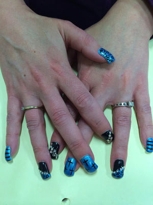 A striking Binh's manicure featuring black and jewel design elements against a blue blackground