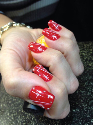 A woman displaying her red polish manicure with white Christmassy adornments from Binh's in Edmonton