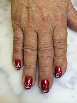 Warm, red polish with a matching white design element on each finger looks lovely on this Binh's creation