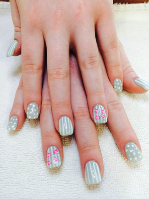 Delicate fingers displaying polished nails in greys, whites and "just been kissed" designs at Binh's salon