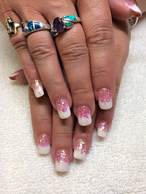 A woman displaying her manicure featuring pink glitter with white tips she received from the nail experts at Binh's.