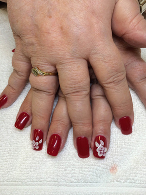 A woman's fingers stylized with deep red polish and white flower appliques from Binh's on 17th Street