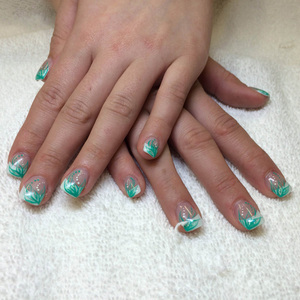 An ornate manicure featuring light green and white highlights created by the nail artisans at Binh's East