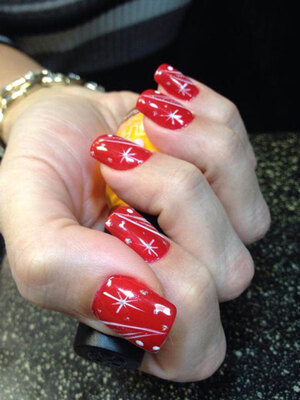 A lady's hand with squared gel nails featuring a blood red base with white accents from Binh's nail technicians