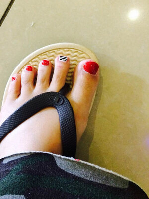 Shapely feet with red polish on four nails and B&W stripes on one from Binh's Salon.